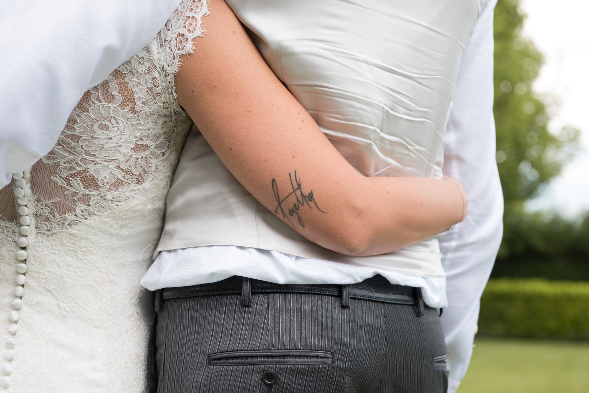 sposa che abbraccia lo sposo e dettaglio tatuaggio