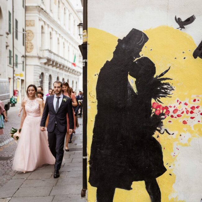 Sposi passeggiano in centro a Padova vicino a un murale di kenny random