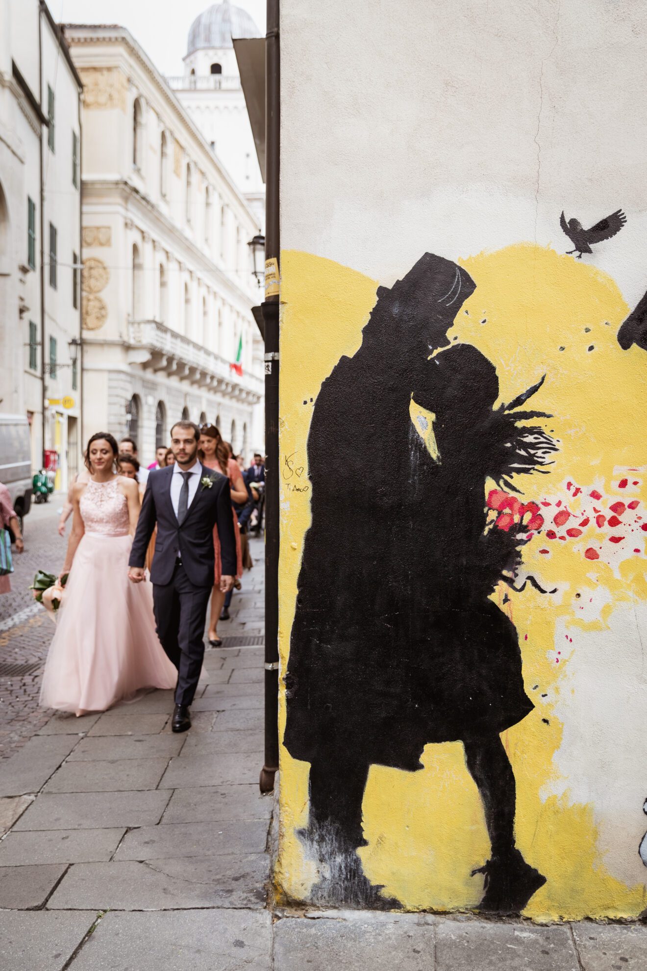 Sposi passeggiano in centro a Padova vicino a un murale di kenny random
